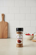 Koshe Suya BBQ Spice jar on a kitchen counter with a wooden chopping board